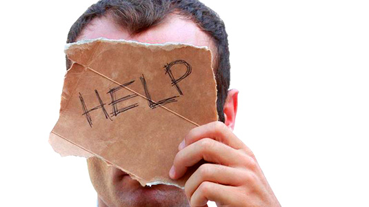 Man holds cardboard sign reading, "help" in front of his face.