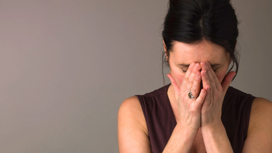 Women holds her face in her hands in sadness. 