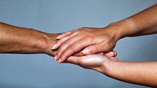 Woman's hands hold a man's hand in a comforting way. 