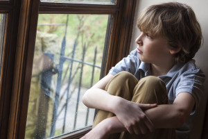 Sad Young Boy Looking Out Window